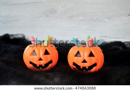 Plastic pumpkin buckets with candy on black spider web background