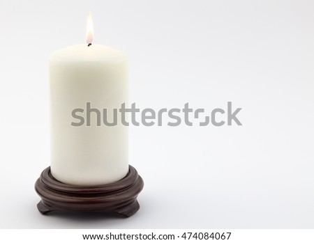 Single white lit candle on wood stand isolated on white background Royalty-Free Stock Photo #474084067