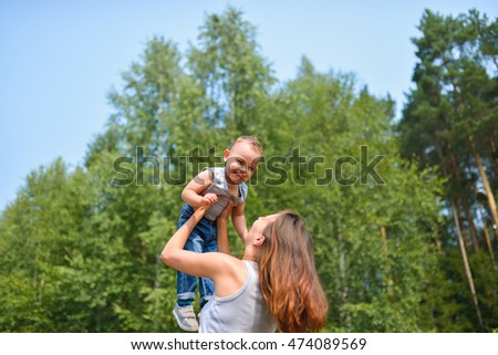 Happy family outdoors. mother throws baby up, laughing and playing in summer on the nature