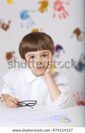 Schoolboy of 7 years old dressed in a shirt,sitting at the table. Back to school
