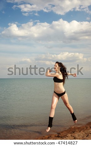 Active sportive lady running and jumping at the beach
