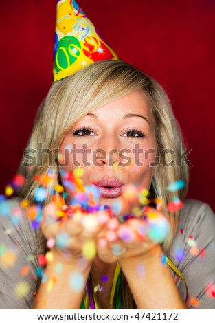 Cheerful lifestyle party celebrating girl with blowing confetti to camera