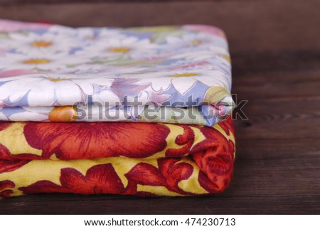 Fabric yellow with red flowers and a blue fabric with white flowers on a dark wooden background.