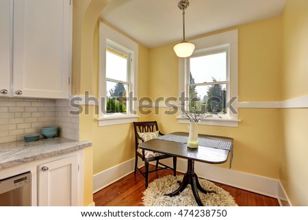 Small dining room area with yellow walls. Compact size table with one chair on a Round soft shaggy carpet. Northwest, USA