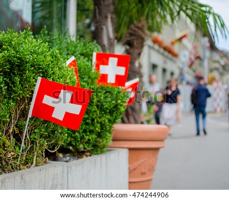 National day in Switzerland. Swiss flags hang in a row outdoor. Soft focus blurry background space for your text. Photo taken on Swiss National Day in Bern, Switzerland.