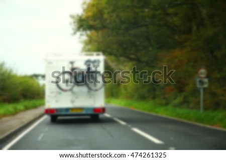 The blurry photo of back side camping car with bicycle at the rear rack scenic from the car windscreen represent the vehicle and traffic control concept related idea.