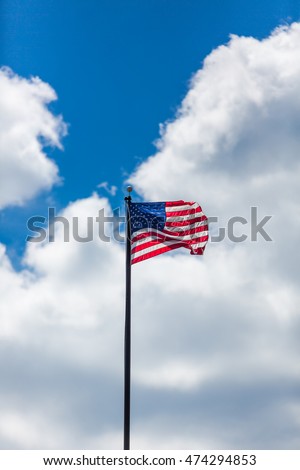 American Flag against blue sky and clouds 