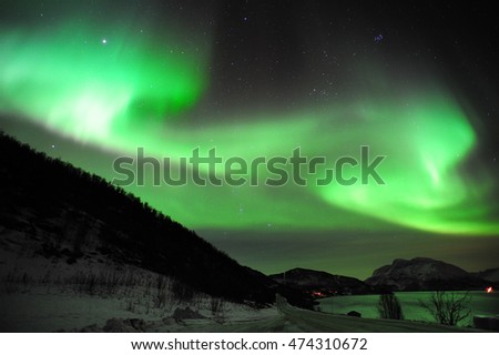 Northern lights over the hills and fjord near Tromso, Northern Norway.