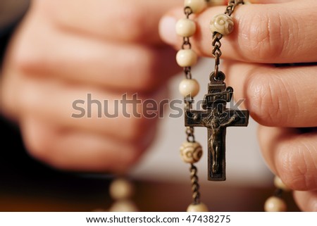Woman (only closeup of hands to be seen) with rosary sending a prayer to God, the dark setting suggests she is sad or lonely Royalty-Free Stock Photo #47438275
