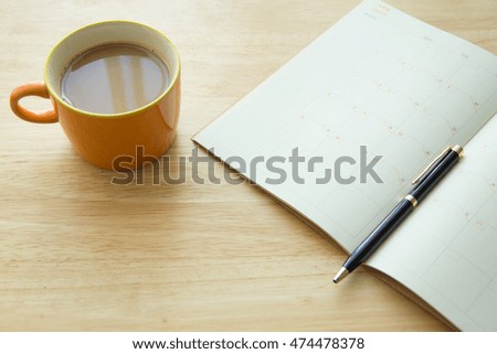 calendar planner with coffee on wood table in the morning, natural day light, selective focus, space for copy