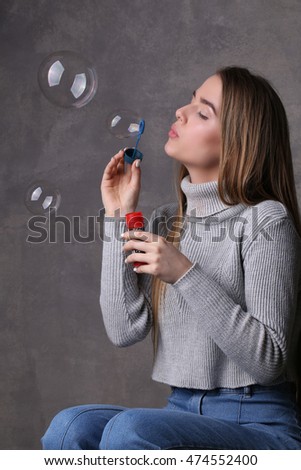 Blonde blowing bubbles. Close up. Gray background