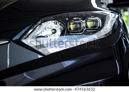 The black sport car has projector / LED headlights, reflections of modern luxury technology and auto detailing.