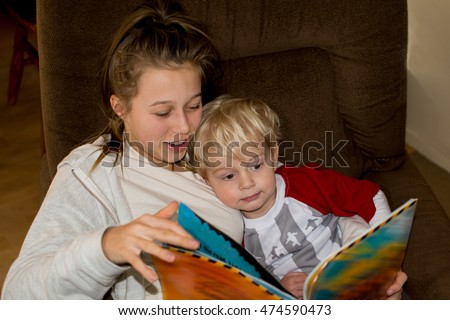 Teenage girl reading book with her younger brother