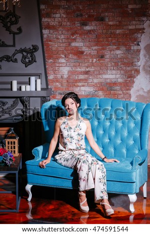 Beautiful woman with styling hairstyles on luxory loft interer background the fireplace chandelier. Blue sofa brick wall in the background