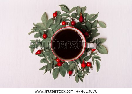 Cup of coffee on a white background in green leaves and red berries, flowers.Flat lay, top view