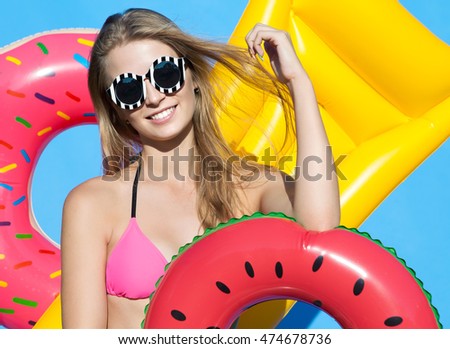Summer beach style portrait a beautiful smiling happy young blonde woman wearing bikini and sunglasses with inflatable swimming pool toys