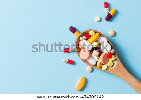 Assorted pharmaceutical medicine pills, tablets and capsules on wooden spoon Royalty-Free Stock Photo #474705142