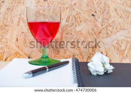 Red wine on black notebook on wood background,working,no have idea