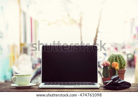 Laptop on wooden table, with cup of coffee and key.  Vintage style