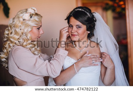 Happy buddies helps bride getting ready for her wedding day in the morning