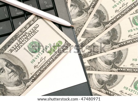 money, business card and pen lying on a laptop