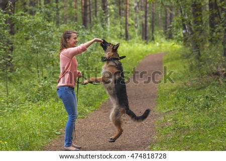 Young woman playing with German shepherd outdoors in the park.