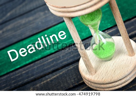 Deadline text and hourglass on wooden table