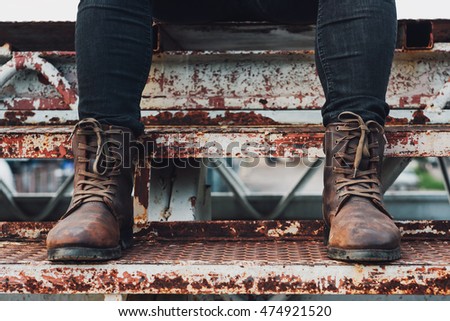 High contrast photo of brown leather boots and black jeans, Men fashion.