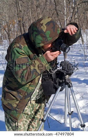 A man with camera in winter forest.