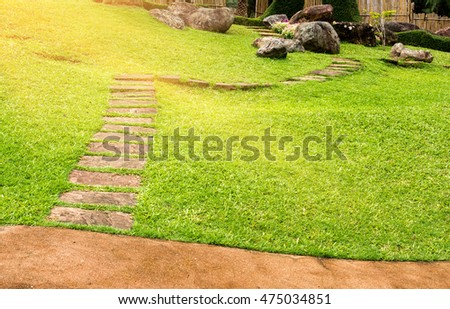 Step up of stones way in green grass with sunbeam