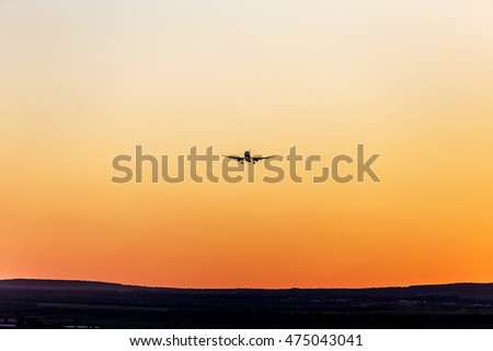 Quick civilian passenger plane in the sky landing to touch the ground. Airplane in the rays of the setting sun in landing mode in airport