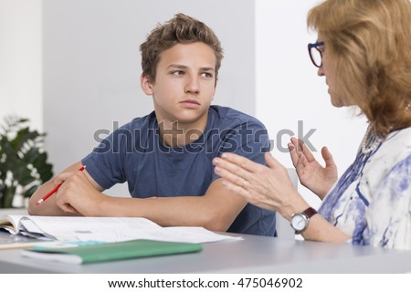 Teenage boy having private lessons with mature teacher, sitting in a light interior Royalty-Free Stock Photo #475046902