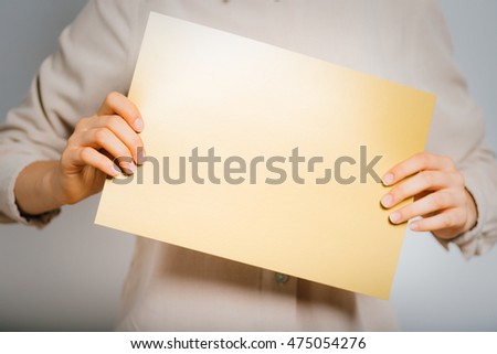 beautiful girl holding a sheet of paper for your text, close-up, isolated on a gray background