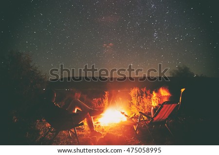 Two friends are sitting around a campfire and just relaxing Royalty-Free Stock Photo #475058995