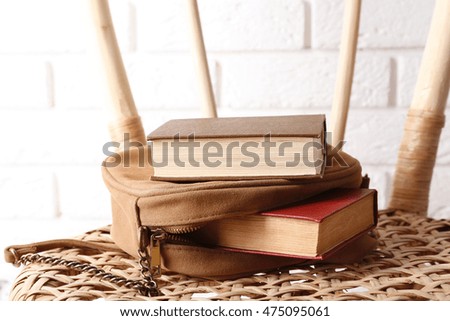 Books with handbag on wicket chair
