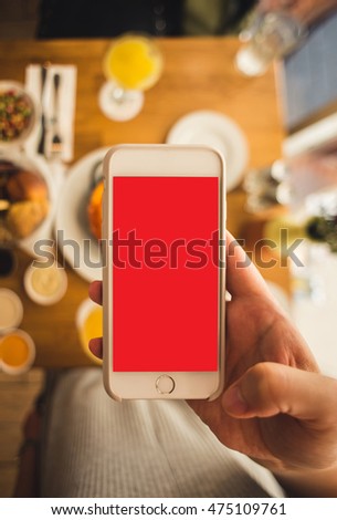 Vertical mock up of a smartphone. Women hold a phone in a hand and taking a picture of breakfast