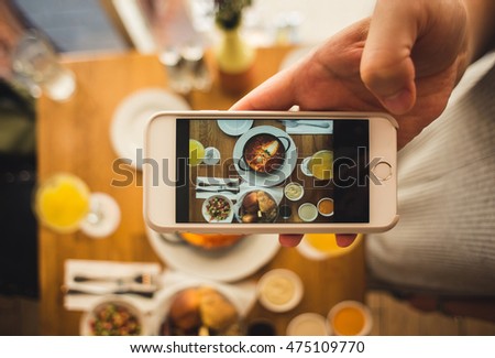 Women hold a smart phone in a hand and taking a picture of breakfast