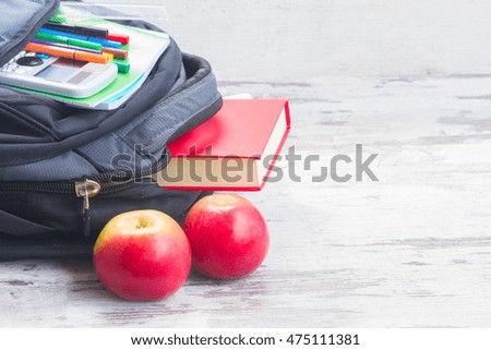 School backpack with supplies and apples on white wooden desktop