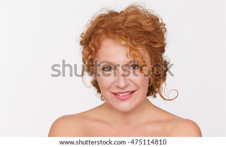 Closeup portrait of beautiful mature woman smiling for camera while posing isolated on white background in studio.