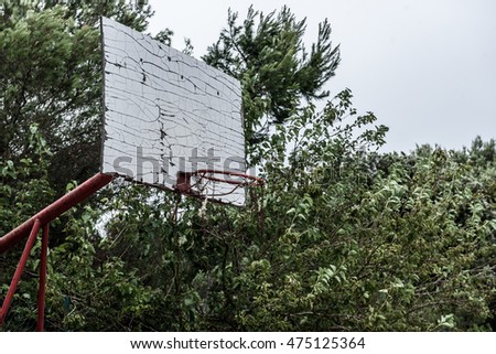 Old abandoned school sports court or schoolyard for different activities. Ruins of a sport venue abandoned long time ago with soccer, handball or football goals, basketball hoops and boards 