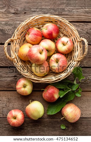 fresh red apples in wicker basket on wooden table