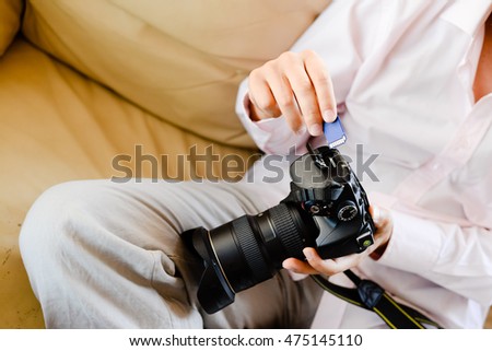 Closeup on person holding DSLR camera in hands. Top side view copy space interior background