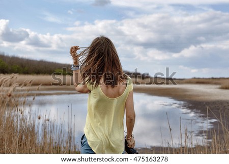 Back portrait of Girl standing on the lake. Alone girl hipster.beautiful nature,traveler concept picture.yellow t-shirt, street style