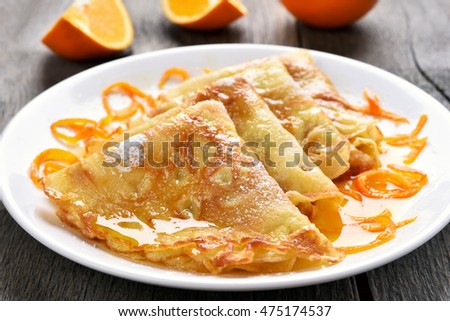 Delicious crepes suzette with orange syrup on plate. Royalty-Free Stock Photo #475174537