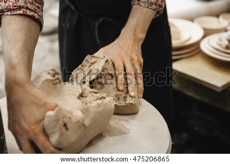 Adult male potter master preparing the clay on table. Front view, closeup, hands only. Art and business, hobby and freelance working concept.