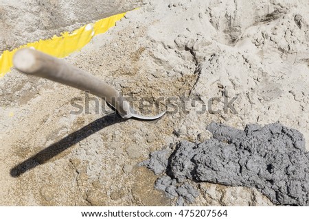 Shovel in sand at the construction site, next to it is fresh mortar.