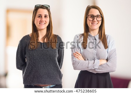 Twin sisters with their arms crossed  on unfocused background
