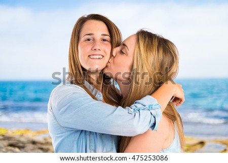 Girl giving kiss at her sister on unfocused background