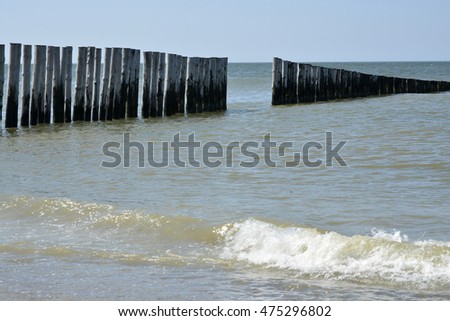 background of empty beach at the coastline of the sea with a row of poles in the surf water