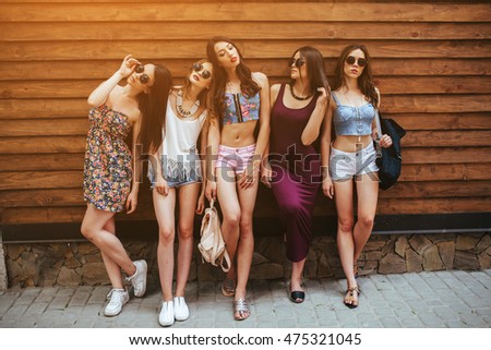 five beautiful girls pose in front of a wooden wall